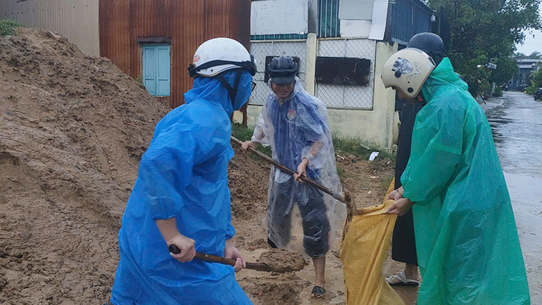 Hỗ trợ người dân chuẩn bị các bao cát để chằng mái nhà.