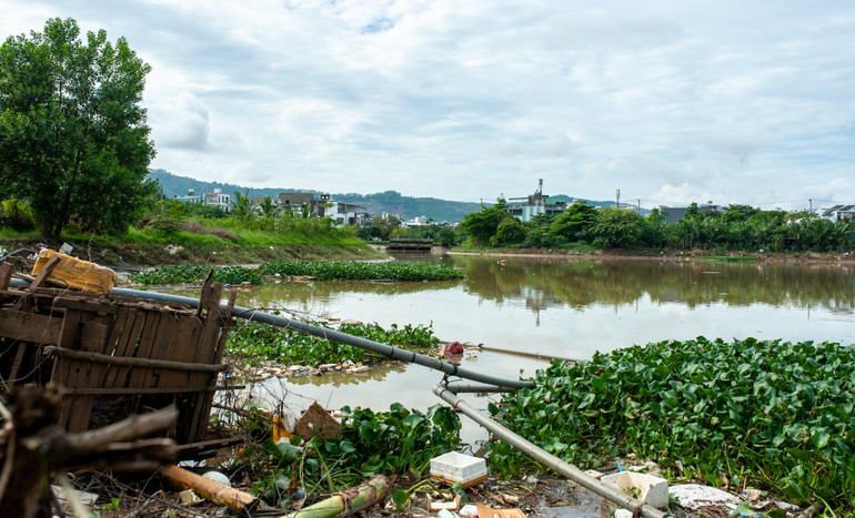 Lúc 10 giờ, tại khu vực hồ điều tiết Hòa Phú, rác thải tiếp tục trôi theo dòng nước, bám dày đặc xung quanh bờ hồ.