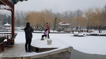 Một gia đình chụp ảnh bên mặt hồ đóng băng trong công viên Nhật Đàn. (Ảnh: HỒ QUÂN)
