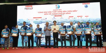 Ông Trương Hòa Bình, nguyên Ủy viên Bộ Chính trị, nguyên Phó Thủ tướng Thường trực Chính phủ, Chủ tịch danh dự của Chương trình và Phó chủ tịch UBND TP Đà Nẵng Trần Chí Cường trao quà hỗ trợ ngư dân Đà Nẵng. (Ảnh: ANH ĐÀO)