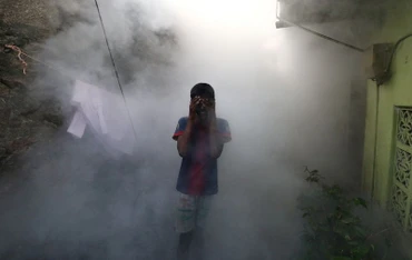 Một cậu bé che mặt để tránh khói khi khi nhân viên y tế hun khói đuổi muỗi phòng sốt xuất huyết tại một khu dân cư ở Colombo, Sri Lanka, ngày 12/7/2023. (Ảnh: Reuters)