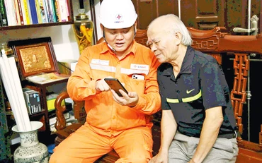Nhân viên điện lực giải thích cho khách hàng tiện ích của việc thanh toán tiền điện qua các ứng dụng. (Ảnh Sơn Đăng)
