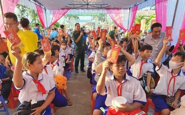 Học sinh biên giới tham dự chương trình chợ Tết yêu thương và nhận bao lì xì từ tay các bộ, chiến sĩ Đồn Biên phòng Sông Trăng, Long An trao. 