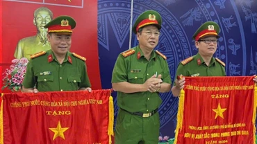 Thừa ủy quyền của Thủ tướng Chính phủ, Đại tá Trần Phòng, Phó Giám đốc Công an thành phố Đà Nẵng trao Cờ thi đua cho hai tập thể. (Ảnh: ANH ĐÀO)
