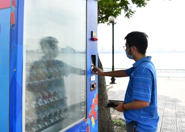 Người dân mua nước uống có đường tại máy bán nước tự động trên địa bàn thành phố Hà Nội. (Ảnh MỸ HÀ) 