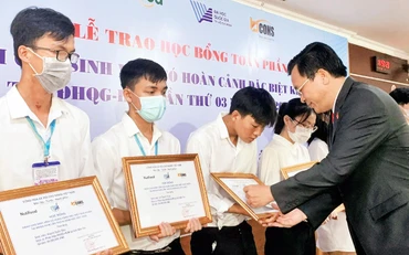 PGS, TS Nguyễn Ðình Tứ, Giám đốc Quỹ Phát triển Ðại học Quốc gia Thành phố Hồ Chí Minh trao học bổng tặng sinh viên mồ côi, khó khăn. (Ảnh: Ðại học Quốc gia Thành phố Hồ Chí Minh). 