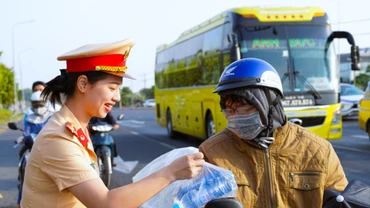 Nữ cảnh sát giao thông phát nước suối, khăn lạnh cho người dân trở lại sau đợt nghỉ Tết sáng 2/2, trên Quốc lộ 1A.