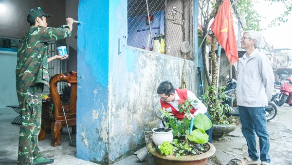 Ông Lê Văn Nam (bên phải) vui mừng khi ngôi nhà được các tình nguyện viên hỗ trợ sơn mới.