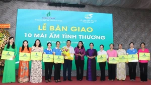 Đại diện Báo Nhân Dân trao bảng tượng trưng bàn giao 10 căn nhà mái ấm tình thương cho phụ nữ có hoàn cảnh khó khăn trên địa bàn. (Ảnh: HOÀNG TRUNG)