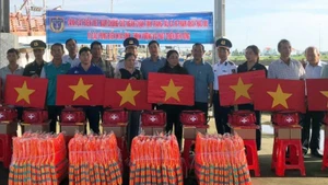 Đại biểu tham dự hội nghị tặng cờ Tổ quốc, áo phao, thiết bị y tế cho ngư dân. (Ảnh: HOÀNG TRUNG)