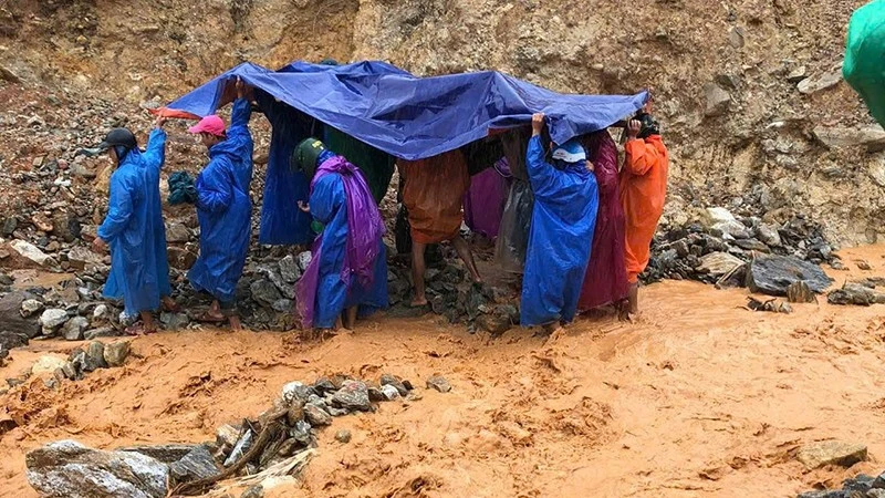 Lực lượng dân quân thường trực xã Trà Leng cùng người nhà dùng võng để khiêng bệnh nhân qua khu vực sạt lở.