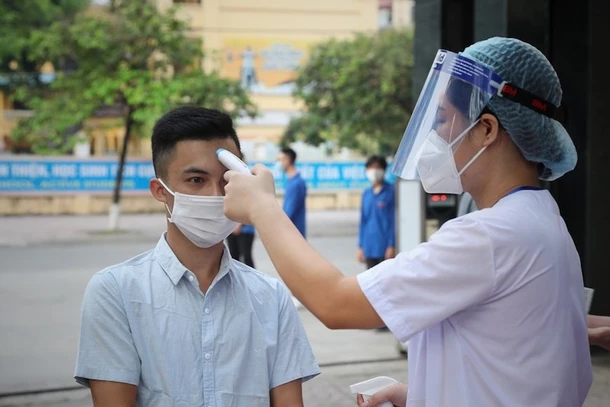 Kiểm tra thân nhiệt cho thí sinh trước khi vào điểm thi tại Hội đồng thi Bắc Giang. Ảnh: DANH LAM/TTXVN