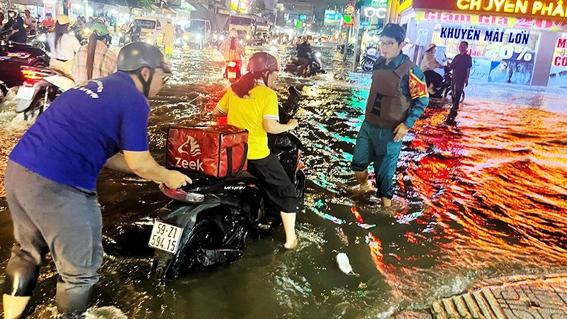 Lực lượng xung kích trợ giúp người dân di chuyển khi triều cường dâng cao.
