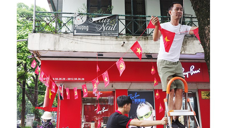 Người dân phường Hoàn Kiếm treo cờ đỏ sao vàng đón ngày đại lễ. Ảnh: ANH QUÂN