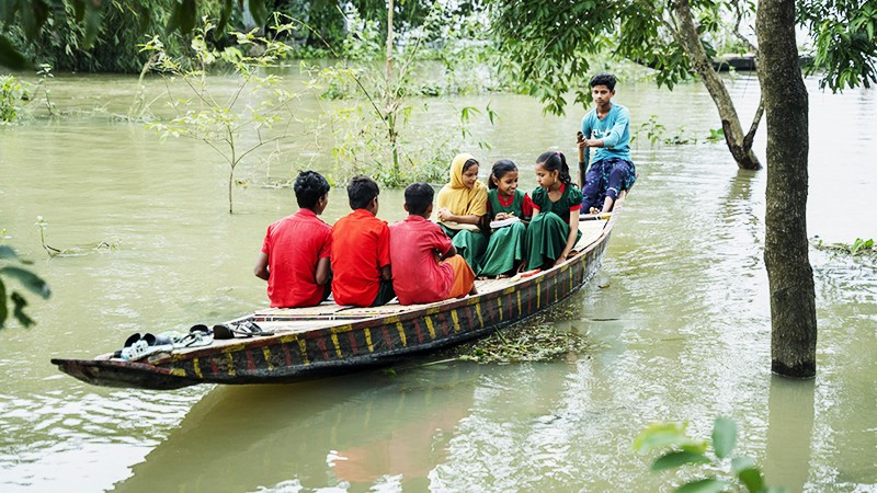 Trẻ em Bangladesh chèo thuyền qua vùng ngập lụt để đến trường. Ảnh: UNICEF