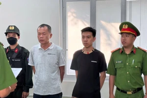 Đặng Trần Quốc Vũ (áo trắng) và Đào Năng Nghĩa (áo đen) nghe đọc lệnh tạm giữ hình sự.