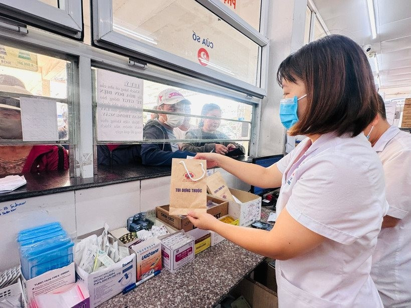 Nhân viên y tế cấp phát thuốc bảo hiểm y tế cho người bệnh. (Ảnh Thùy Giang)