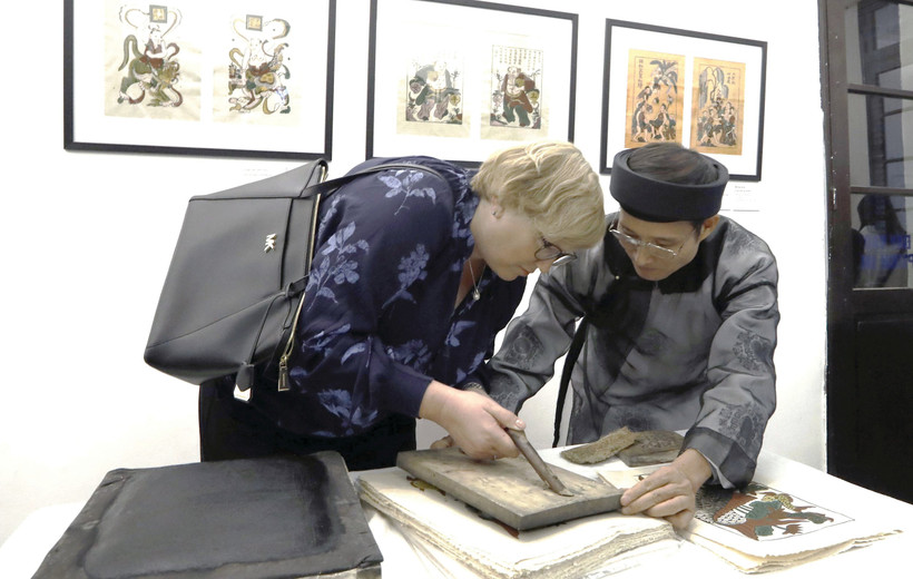 Nghệ nhân Nguyễn Hữu Quả giới thiệu kỹ thuật in tranh Đông Hồ tới du khách quốc tế, tại Bảo tàng Mỹ thuật Việt Nam.