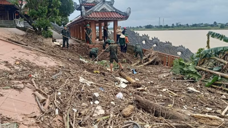 Cán bộ, chiến sĩ Ban Chỉ huy Phòng thủ Khu vực 4-Triệu Phong dọn dẹp rác và bùn tại Bến thả hoa bờ nam sông Thạch Hãn.