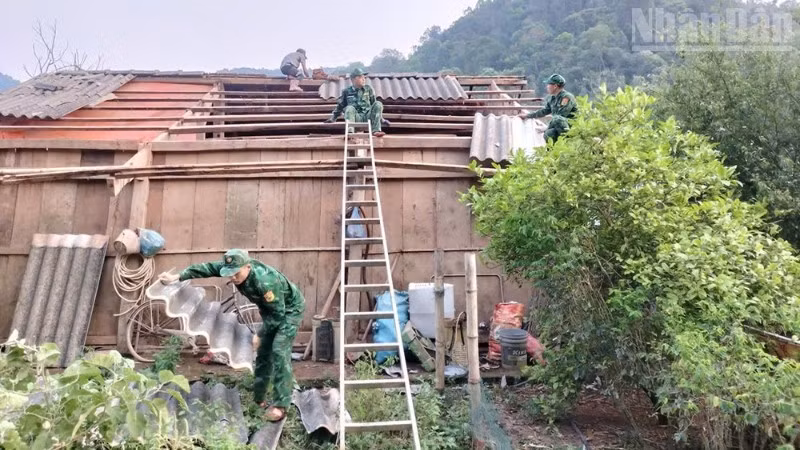 Cán bộ, chiến sĩ Đồn Biên phòng Chiềng Sơn giúp hộ gia đình anh Lò Văn Thực lợp lại mái nhà. (Ảnh: QUÀNG HÙNG)