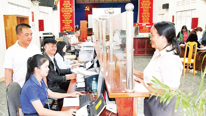 Chủ tịch Ủy ban nhân dân xã Tà Năng Nguyễn Vũ Linh Sang (bìa trái) hướng dẫn cán bộ Trung tâm phục vụ hành chính công xã ứng dụng AI phục vụ người dân làm thủ tục hành chính.