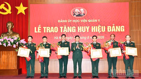 Thiếu tướng, Phó Giáo sư, Tiến sĩ Nguyễn Văn Nam, Ủy viên Ban thường vụ Đảng ủy, Phó Chính ủy Học viện Quân y trao Huy hiệu 35 năm tuổi Đảng và tặng hoa chúc mừng 6 đồng chí thuộc Đảng bộ Học viện Quân y. (Ảnh: TUẤN DŨNG)