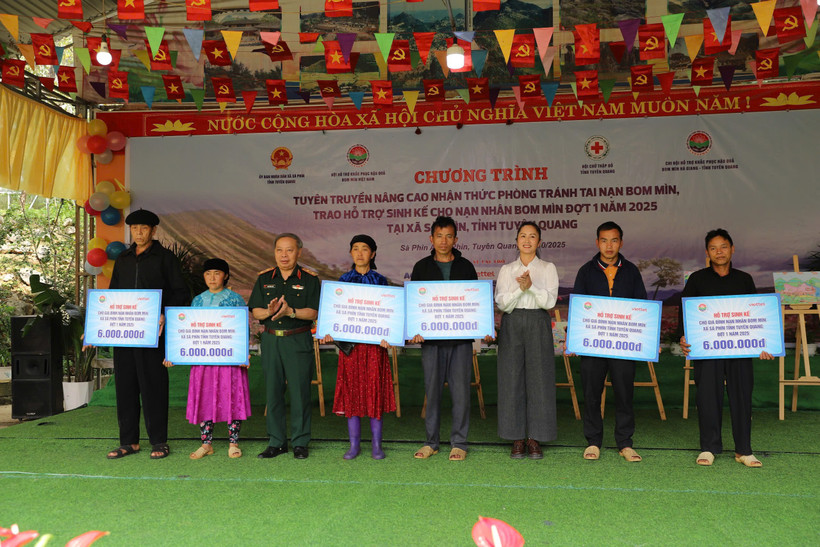 Trung tướng Phạm Ngọc Khóa, Phó Chủ tịch thường trực Hội Hỗ trợ khắc phục hậu quả Bom mìn Việt Nam và đồng chí Lý Thị Kiên, Phó Bí thư thường trực xã Sà Phìn trao hỗ trợ. sinh kế cho gia đình các nạn nhân bom mìn.