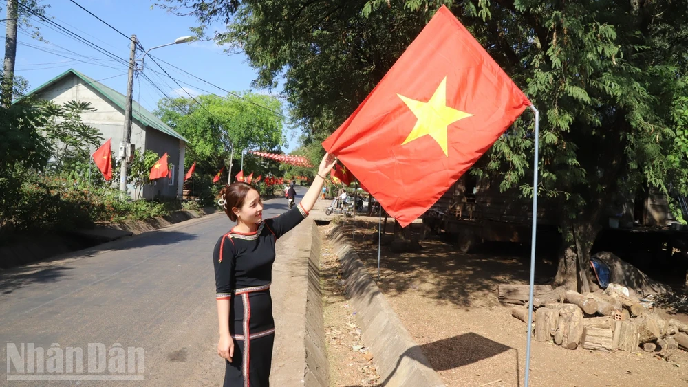 Bí thư Chi bộ buôn Tuôr, xã Hòa Phú H'Lin H'Đớt treo cờ Tổ quốc hướng về Đại hội XIV của Đảng.
