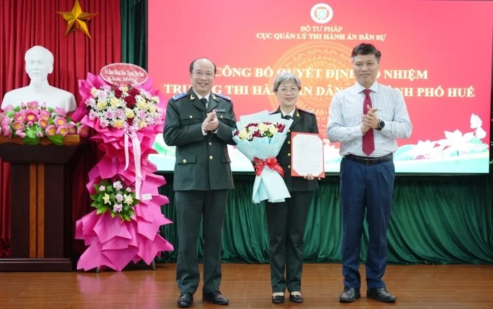 Cục trưởng Cục Quản lý Thi hành án dân sự Nguyễn Thắng Lợi và Trưởng Ban Tổ chức Thành ủy Huế Phan Xuân Toàn trao quyết định, tặng hoa chúc mừng bà Phan Thùy Dương.