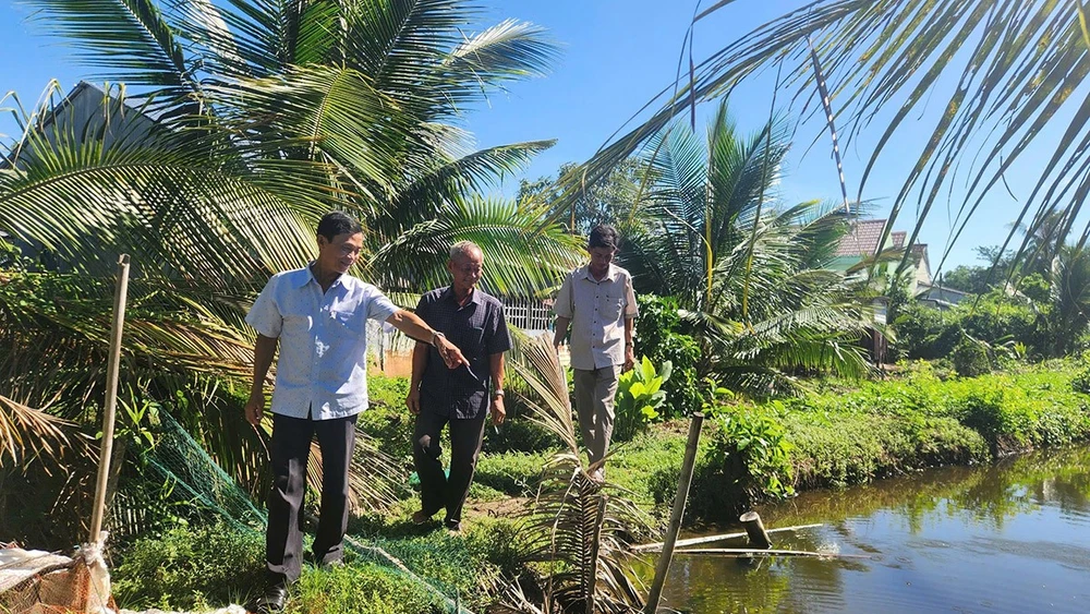 Ông Năm Dậu (giữa) cùng cán bộ địa phương đến tận nơi tìm hiểu, giải quyết ổn thỏa mâu thuẫn trong tranh chấp đất của hai hộ dân.