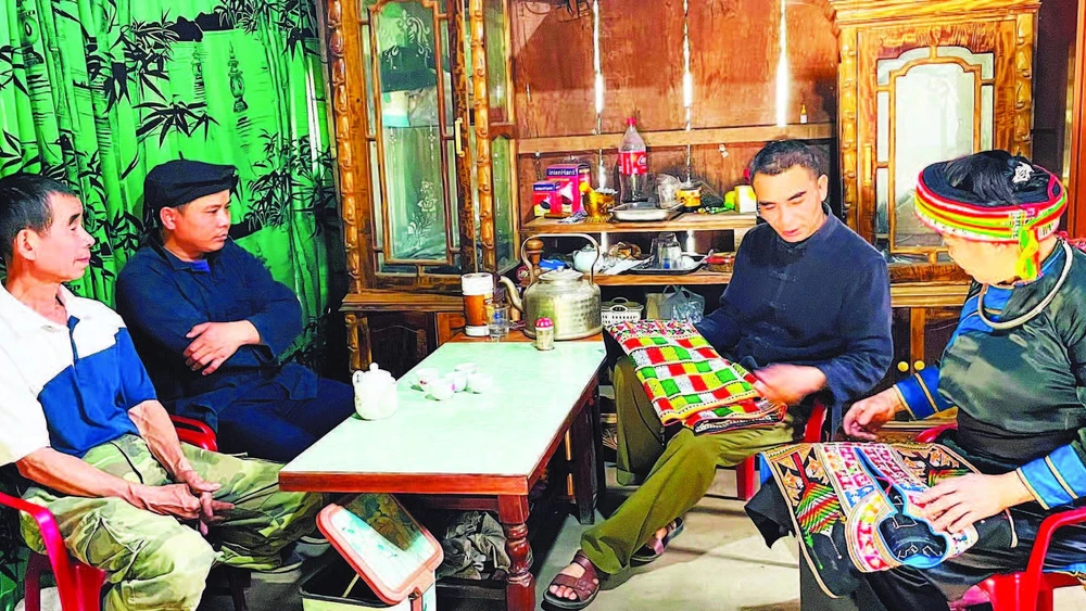 Ông Vũ Trung Huấn (thứ hai từ phải sang), Bí thư Chi bộ, người có uy tín thôn Phiêng Cà-Cọn Poỏng, vận động đồng bào dân tộc Dao giữ gìn nghề thêu truyền thống. (Ảnh THU TRANG)