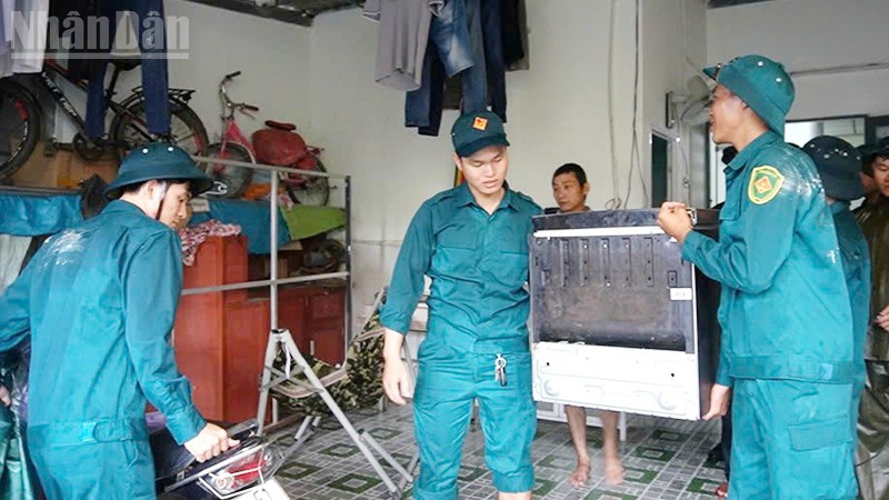 Lực lượng dân phòng hỗ trợ người dân vùng nguy cơ ngập lụt kê cao đồ đạc.