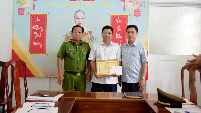 Đại diện Công an huyện Vĩnh Thuận và lãnh đạo xã Vĩnh Bình Bắc trao giấy khen cho anh Nguyễn Xuân Trọn. (Ảnh: Công an xã Vĩnh Bình Bắc cung cấp)