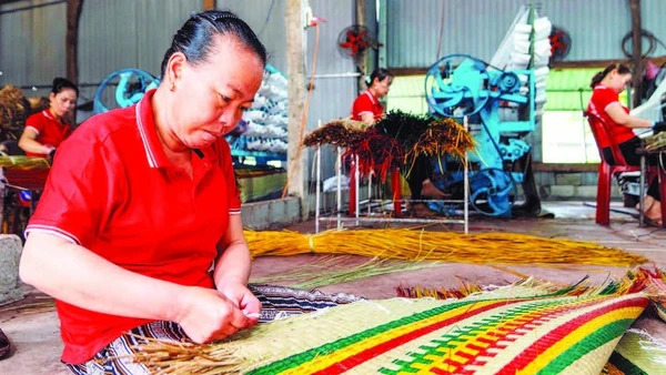 Công nhân Hợp tác xã chiếu cói Hoài Châu Bắc hoàn thiện một công đoạn làm ra chiếc chiếu thành phẩm. (Ảnh MỸ HÀ)