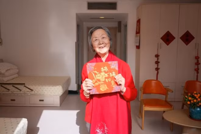Một người phụ nữ lớn tuổi cầm trên tay tác phẩm thủ công của mình tại một trung tâm chăm sóc sức khỏe người cao tuổi. (Ảnh: Tân Hoa Xã)
