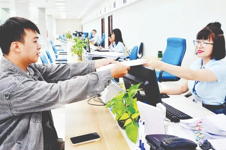 Cán bộ Trung tâm Phục vụ hành chính công tỉnh Quảng Ninh tiếp nhận, xử lý hồ sơ của công dân. (Ảnh THANH HOA)