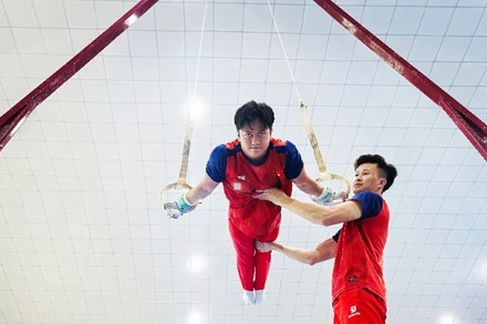 Huấn luyện viên Trương Minh Sang hỗ trợ vận động viên trong bài tập vòng treo.