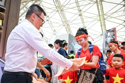 Tổng Biên tập Báo Nhân Dân Lê Quốc Minh phát phụ san đặc biệt của Báo Nhân Dân tới bạn đọc trẻ tại Triển lãm “80 năm Hành trình Độc lập - Tự do- Hạnh phúc”. (Ảnh: THÀNH ĐẠT)