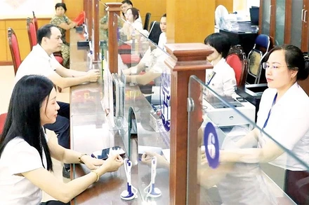 Giải quyết thủ tục hành chính cho người dân tại điểm phục vụ hành chính công phường Thanh Xuân. (Ảnh QUANG THÁI)