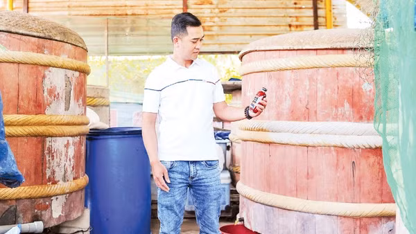Anh Võ Nguyên Tùng, Trưởng ban làng nghề truyền thống nước mắm Cửa Khe, bên những thùng gỗ ủ mắm của mình.