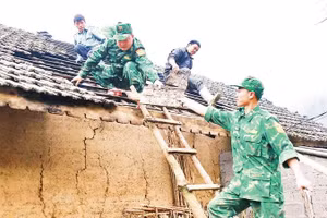 Cán bộ, chiến sĩ Đồn Biên phòng Tùng Vài giúp gia đình chị Hầu Thị Mái, thôn Lùng Khố lợp lại mái nhà bị hư hỏng sau thiên tai.