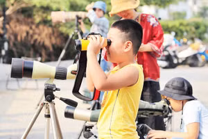 Các em nhỏ trải nghiệm ống nhòm chuyên dụng. 