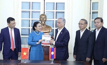 Bà Nguyễn Phương Nga tặng Chủ tịch Ủy ban Hòa bình và Đoàn kết Lào Sommad Pholsena cuốn đặc san "60 năm hữu nghị Việt Nam-Lào: Chung dãy Trường Sơn" của Tạp chí Thời Đại. (Nguồn: Báo Hà Nội mới)