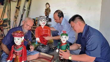 Nghệ nhân Tiến Hòa (trái) cùng các diễn viên trong đoàn chỉnh sửa con rối trước khi biểu diễn.