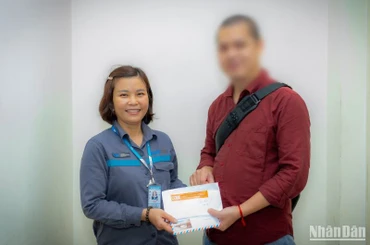 Chị Tươi trao lại chiếc túi chứa 4.300 USD cho anh V.Q.Đ. trong niềm vui sướng của anh.
