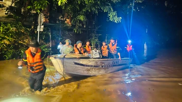 Lực lượng công an dùng thuyền vượt nước lũ cứu dân. (Ảnh: THANH SƠN)