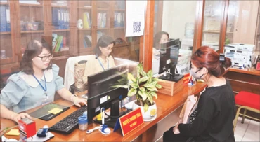 Công chức tại Bộ phận một cửa UBND phường Hàng Bài giải quyết thủ tục hành chính cho người dân. (Ảnh Duy Linh)