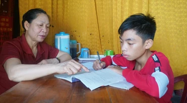 Mẹ đỡ đầu Trương Thị Hiển hướng dẫn cháu Cao Xuân Sỹ học bài.
