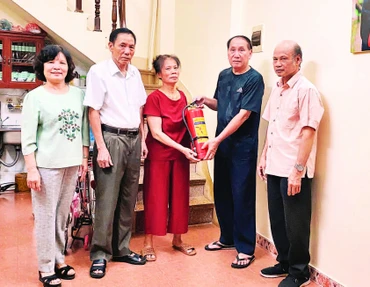 Đại diện Chi bộ 11 trao tặng bình cứu hỏa cho gia đình cựu chiến binh.
