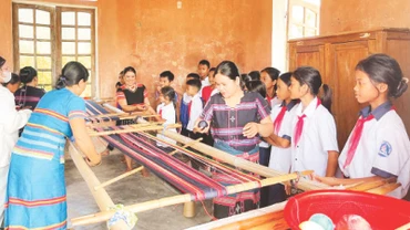 Những người thợ lành nghề hướng dẫn các em học sinh kỹ thuật lên khung dệt thổ cẩm.